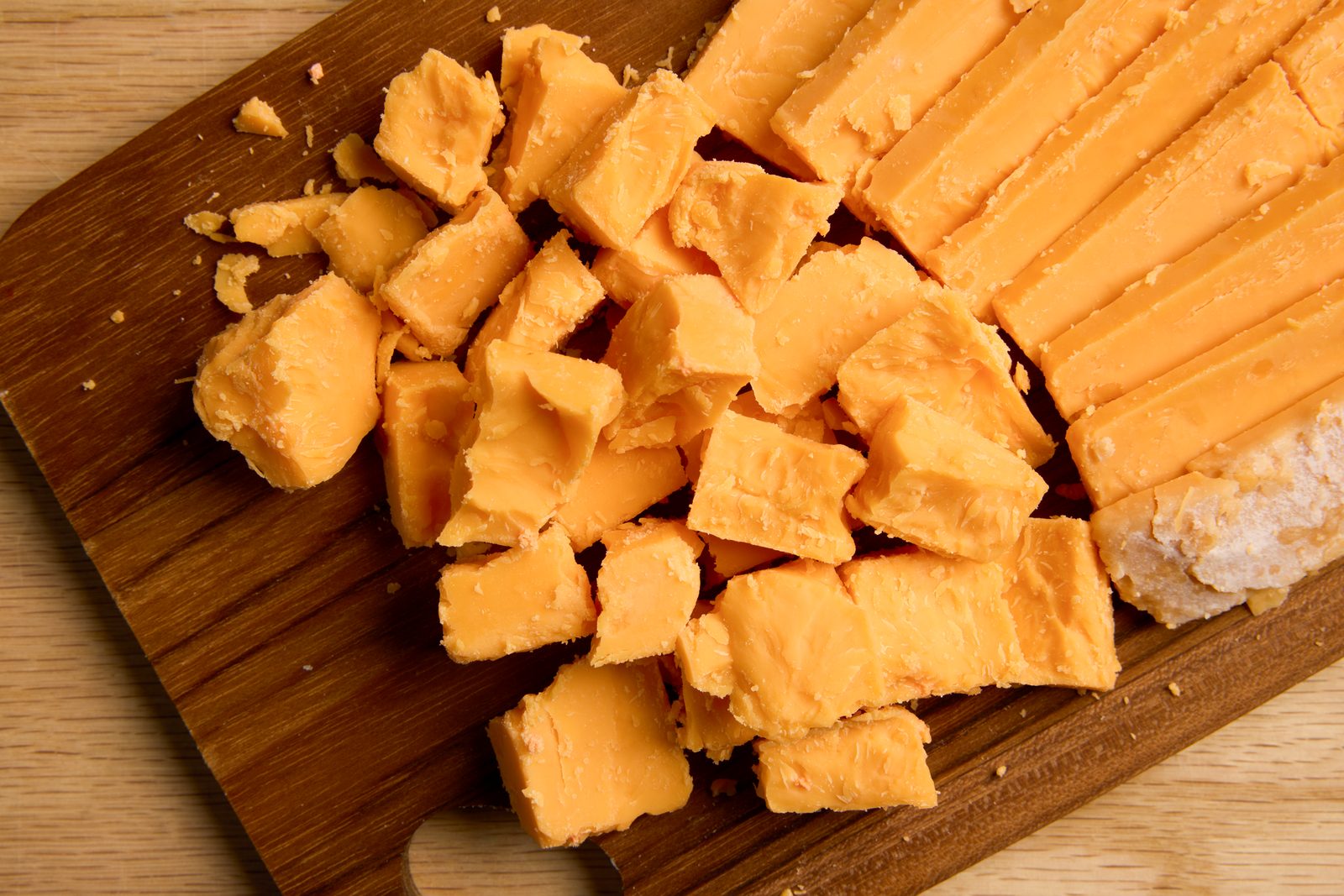 Crumbled aged cheddar on a wooden cutting board